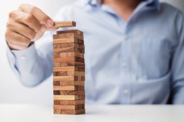 Yerleştirme veya ahşap blok kule çekerek işadamı el. İş planlama, Risk Yönetimi, çözüm ve strateji kavramları