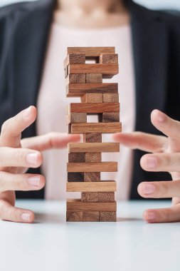 İş kadını el kaplaması kuledeki tahta bloğu kaplıyor. İş planlaması, Risk Yönetimi, Çözüm, Sigorta ve Strateji Konseptleri
