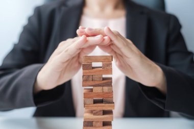 İş kadını el kaplaması kuledeki tahta bloğu kaplıyor. İş planlaması, Risk Yönetimi, Çözüm, Sigorta ve Strateji Konseptleri