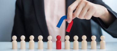 İş kadını mıknatıs tutuyor ve kalabalık çalışanından tahta adam figürü alıyor. İş, İnsan Kaynakları Yönetimi, İşe Alma, Takım Çalışması, Strateji, Zehirli İnsanlar ve Liderlik Kavramları