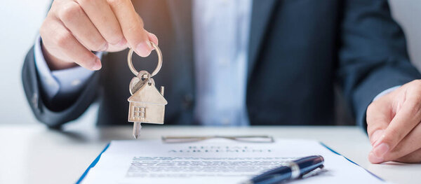 man holding home key during signing home contract documents. Contract agreement, real estate,  buy and sale and insurance concepts