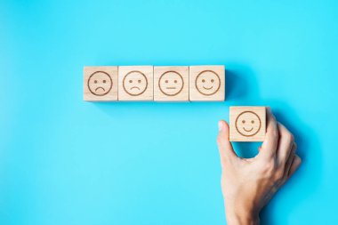 Elele tutuşan bir adam yüz bloğu. Müşteri, kullanıcı değerlendirmeleri için Emoticon 'u seçer. Hizmet derecesi, sıralama, müşteri değerlendirmesi, memnuniyet, değerlendirme ve geri bildirim kavramı