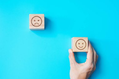 Elele tutuşan bir adam yüz bloğu. Müşteri, kullanıcı değerlendirmeleri için Emoticon 'u seçer. Hizmet derecesi, sıralama, müşteri değerlendirmesi, memnuniyet, değerlendirme ve geri bildirim kavramı