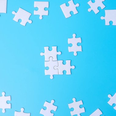 Mavi arka planda beyaz yapboz parçaları grubu. Çözüm kavramı, görev, başarı, hedefler, işbirliği, ortaklık, strateji ve bulmaca günü