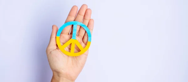 Support for Ukraine in the war with Russia, Hands holding symbol of peace with flag of Ukraine. Pray, No war, stop war, stand with Ukraine and Nuclear Disarmament