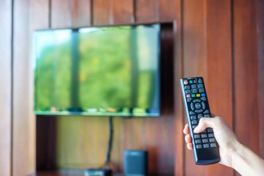 Ev veya lüks oteldeki modern odadaki Smart TV 'yi ayarlamak için uzaktan kumanda kullanılıyor.