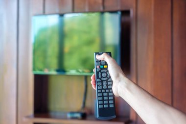 Ev veya lüks oteldeki modern odadaki Smart TV 'yi ayarlamak için uzaktan kumanda kullanılıyor.