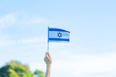 İsrail bayrağını doğa arka planında tutan el. İsrail 'in Bağımsızlık Günü ve mutlu kutlamalar