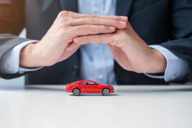 İş adamı el örtüsü ya da masadaki kırmızı araba oyuncağı. Araba sigortası, garanti, onarım, finans, bankacılık ve para kavramı