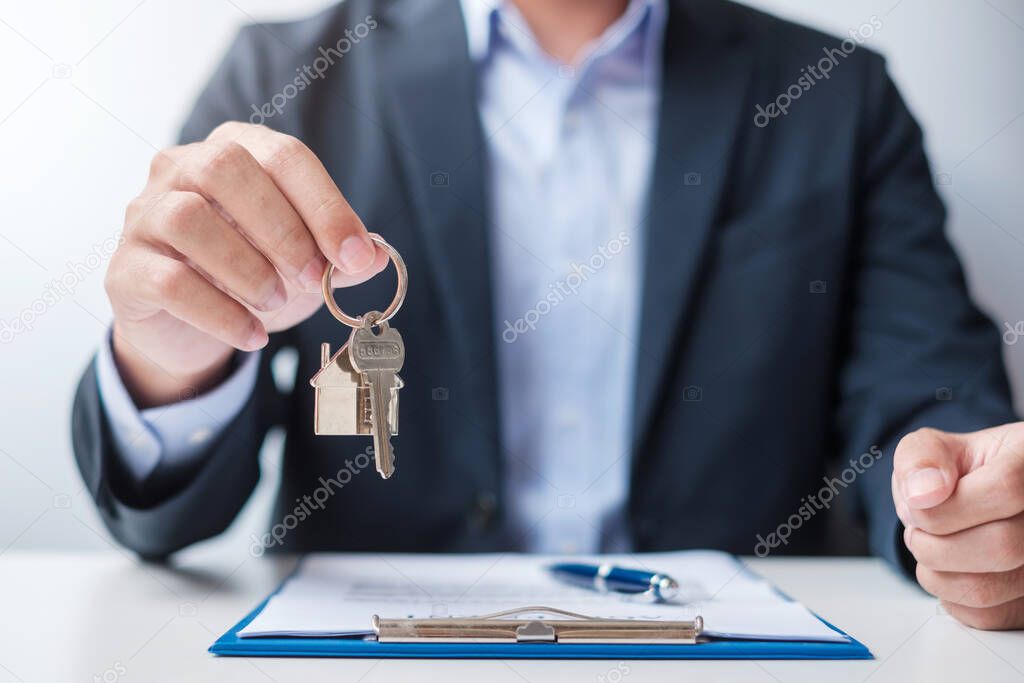 man holding home key during signing home contract documents. Contract agreement, real estate,  buy and sale and insurance concepts