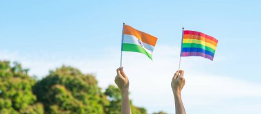 Doğa arka planında LGBTQ Gökkuşağı ve Hindistan bayrağını gösteren eller. Lezbiyen, Gey, Biseksüel, Transseksüel ve Eşcinsel Topluluğuna ve Gurur Ayı kavramına destek