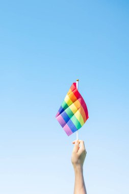 hands showing LGBTQ Rainbow flag on nature background. Support Lesbian, Gay, Bisexual, Transgender and Queer community and Pride month concept