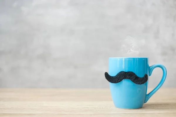 Blue coffee cup or tea mug with Black mustache decor on table. Blank copy space for text. Blue November, Happy Father day and International men day concept