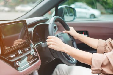 woman driver driving a car on the road, hand controlling steering wheel in electric modern automobile. Journey, trip and safety Transportation concepts
