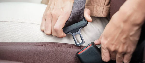 woman driver hand fastening seat belt during sitting inside a car and driving in the road. safety, trip, journey and transport concept