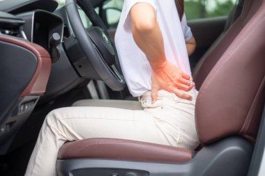 Uzun süre araba kullanırken sırtı burkulmuş bir kadın. Piriforis Sendromu, bel ağrısı ve omurga sıkışması nedeniyle sırt ağrısı çekiyor. Ergonomik ve tıbbi konsept