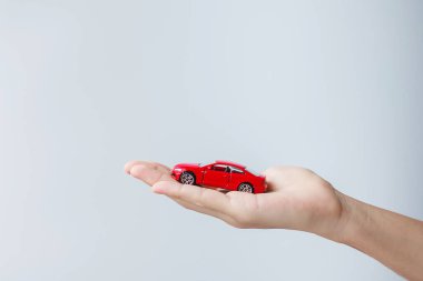 İş adamı eli kırmızı araba oyuncağını tutuyor. Araba sigortası, garanti, kira, finans, yeni ve onarım konsepti