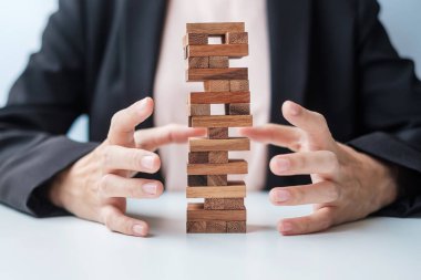 İş kadını el kaplaması kuledeki tahta bloğu kaplıyor. İş planlaması, Risk Yönetimi, Çözüm, Sigorta ve Strateji Konseptleri
