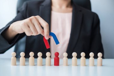 İş kadını mıknatıs tutuyor ve kalabalık çalışanından tahta adam figürü alıyor. İş, İnsan Kaynakları Yönetimi, İşe Alma, Takım Çalışması, Strateji, Zehirli İnsanlar ve Liderlik Kavramları