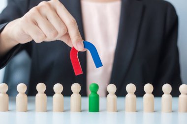 İş kadını mıknatıs tutuyor ve kalabalık çalışanından tahta adam figürü alıyor. İş, İnsan Kaynakları Yönetimi, İşe Alma, Takım Çalışması, Strateji, Zehirli İnsanlar ve Liderlik Kavramları