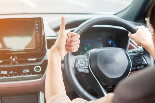 在现代电动汽车中 妇女在路上开车时手拿着拇指 手拿着方向盘 旅行和安全运输概念 — 图库照片