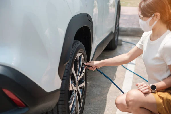 Woman driver hand inflating tires of vehicle, checking air pressure and filling air on car wheel at gas station. self service, maintenance and safety transportation concept