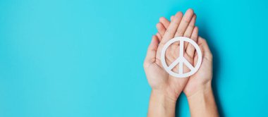 Uluslararası Barış Günü. Mavi arka planda beyaz kağıt, barış sembolü tutan eller. Özgürlük, Umut, Dünya Barışı Günü 21 Eylül ve Nükleer Silahsızlanma Kavramları..