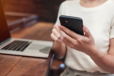 Casual Businesswoman using smartphone and laptop, freelance woman typing keyboard computer notebook in cafe or modern office. technology, digital online and network concept