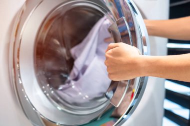 Ev hanımı Kadın çamaşır odasında Çamaşır Makinesi içinde giysi tutan kadın el