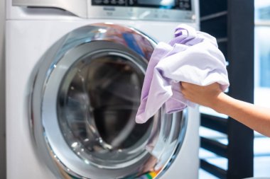 Ev hanımı Kadın çamaşır odasında Çamaşır Makinesi içinde giysi tutan kadın el