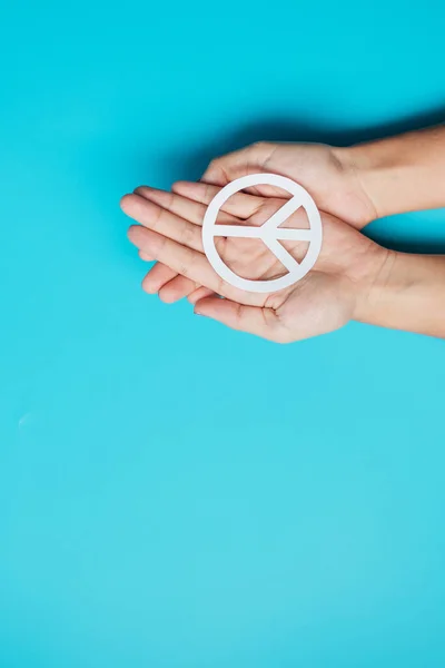 International Day of Peace. Hands holding white paper Peace symbol on blue background. Freedom, Hope, World Peace day 21 September and Nuclear Disarmament concepts..