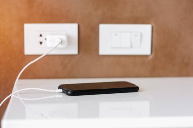 Cep telefonunun şarjı evde ya da ofiste şarj oluyor. Teknoloji, çoklu paylaşım ve yeniden yükleme kavramları