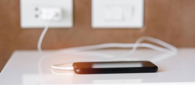 Cep telefonunun şarjı evde ya da ofiste şarj oluyor. Teknoloji, çoklu paylaşım ve yeniden yükleme kavramları