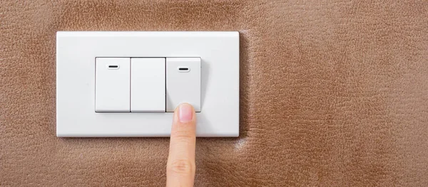 finger turn on or off on light switch on wall at home. Energy Saving, power, electrical and lifestyle concepts