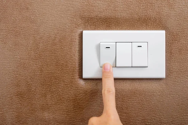 finger turn on or off on light switch on wall at home. Energy Saving, power, electrical and lifestyle concepts