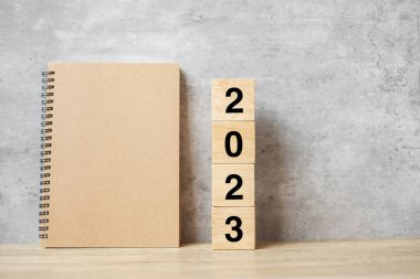 Boş defter ve ahşap numarayla 2023 mutlu yıllar. Geri sayım, Çözüm, Hedefler, Plan, Eylem ve Görev Konsepti