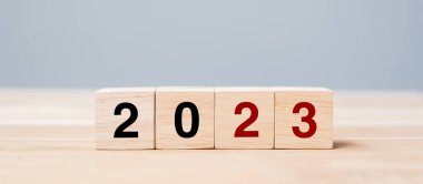 Masa arkasında 2023 metni olan tahta küp bloğu. Çözüm, plan, gözden geçirme, hedef, başlangıç ve yeni yıl tatili kavramları