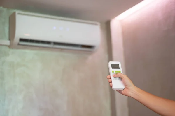 hand using remote controller for adjust Air conditioner inside the room of office or home