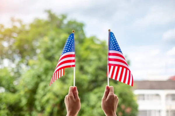 hand holding United States of America flag on green background. USA holiday of Veterans, Memorial, Independence ( Fourth of July) and Labor Day concept