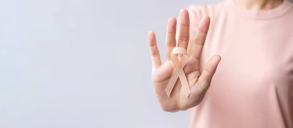 9月子宮がん啓発月間 ピーチリボン を手に持つ女性 医療と世界のがんの日のコンセプト — ストック写真