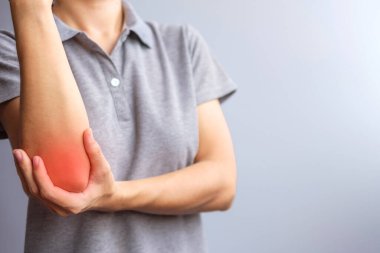 adult female with her muscle pain on gray background. Woman having elbow ache due to lateral epicondylitis or tennis elbow. injuries and medical concept