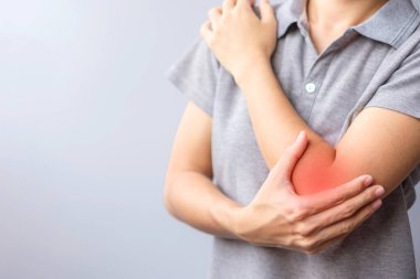 adult female with her muscle pain on gray background. Woman having elbow ache due to lateral epicondylitis or tennis elbow. injuries and medical concept