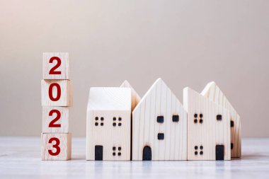 2023 Happy New Year with house model on table wooden background. Banking, real estate, investment, financial, savings and New Year Resolution concepts