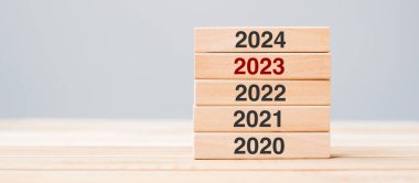 2024 block over 2023 and 2022 wooden building on table background. Business planning, Risk Management, Resolution, strategy, solution, goal, New Year New You and happy holiday concepts