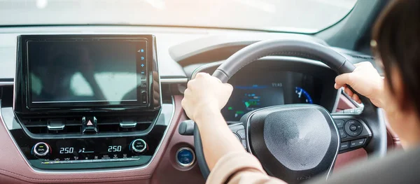 woman driver driving a car on the road, hand controlling steering wheel in electric modern automobile. Journey, trip and safety Transportation concepts