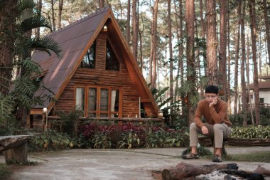 Happy man in sweater traveling in pine tree forest, tourist visit at Doi Bo Luang, Chiang Mai, Thailand, Landmark and popular for tourist attractions. Vacation and journey concept