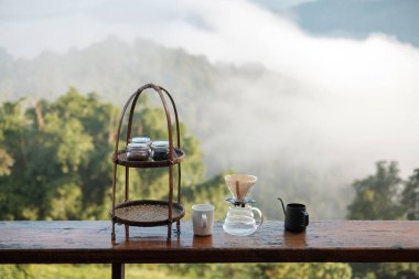 arabica coffee brewing by Vintage coffee drip equipment set on wooden table in the morning with mountain and nature background