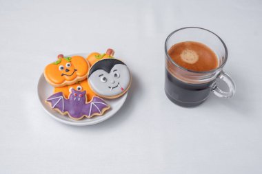Sıcak espresso kahvesi ya da komik Cadılar Bayramı kurabiyeleriyle çikolata fincanı. Mutlu Cadılar Bayramı, Trick or Threat, Hello October, güz, geleneksel, parti ve tatil konsepti