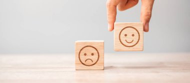 Elele tutuşan bir adam yüz bloğu. Müşteri, kullanıcı değerlendirmeleri için Emoticon 'u seçer. Hizmet derecesi, sıralama, müşteri değerlendirmesi, memnuniyet, değerlendirme ve geri bildirim kavramı