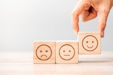 Elele tutuşan bir adam yüz bloğu. Müşteri, kullanıcı değerlendirmeleri için Emoticon 'u seçer. Hizmet derecesi, sıralama, müşteri değerlendirmesi, memnuniyet, değerlendirme ve geri bildirim kavramı